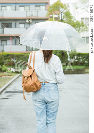 後面觀點的走與一把傘的婦女在毛毛雨城市 38946072