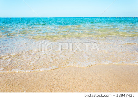 Soft waves with foam of blue ocean on the beach 38947425