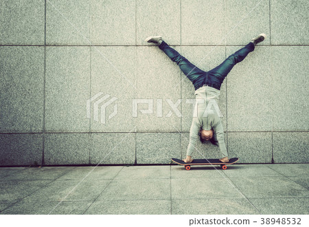 skateboarder handstand on skateboard against wall 38948532