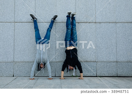Two hipsters doing handstand against wall in city Two hipsters doing handstand against wall in city 38948751