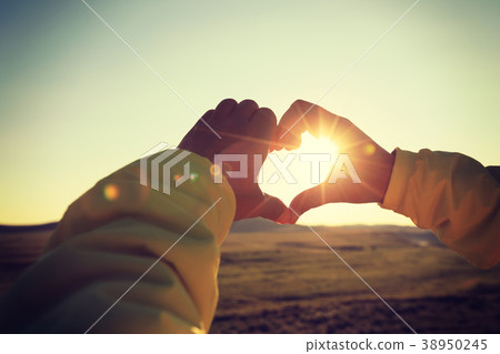 hands making Heart shaped sign over sunset sky . hands making Heart shaped sign over sunset sky . 38950245