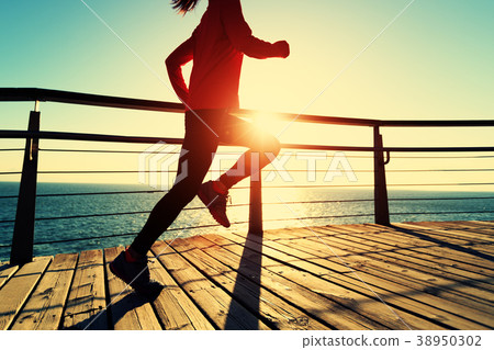 runner running on seaside boardwalk during sunrise 38950302