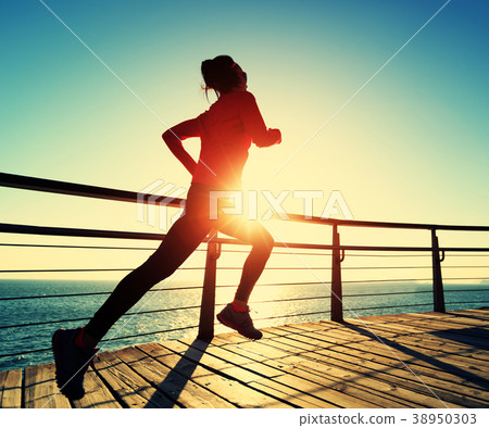 sporty runner running on seaside boardwalk   38950303