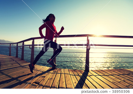 sporty runner running on seaside boardwalk   38950306