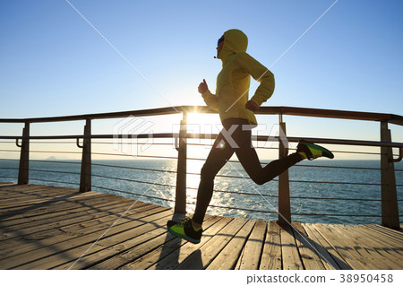 sporty fitnessrunner running on seaside boardwalk  38950458