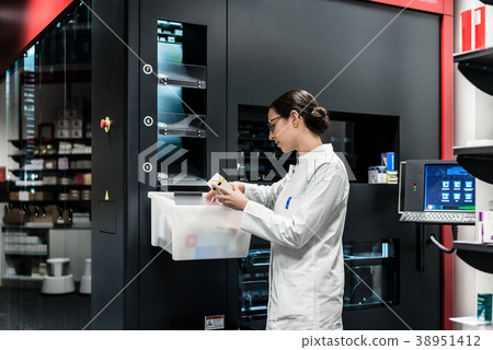 Pharmacist using a computer while managing the 38951412