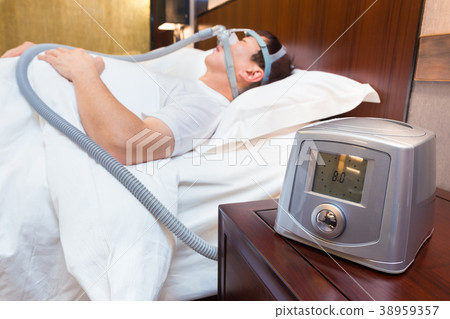 CPAP machine on a bedside table,middle age man 38959357