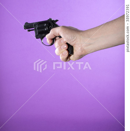 Revolver in a man's hand on a purple background 38972391