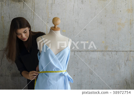 Asian female clothing designer using dress dummy 38972754