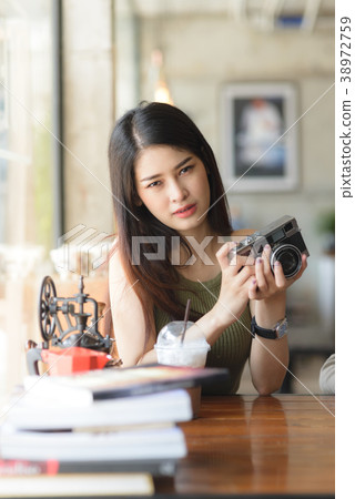Happy Asian woman holding vintage camera in cafe 38972759