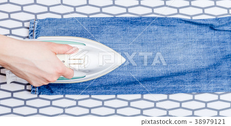 Picture of man ironing blue jeans on board Picture of man ironing blue jeans on board 38979121