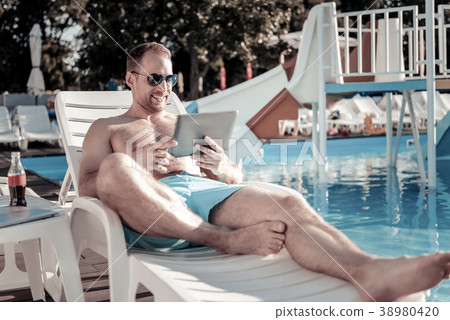 Joyful millennial gentleman using tablet computer Joyful millennial gentleman using tablet computer 38980420