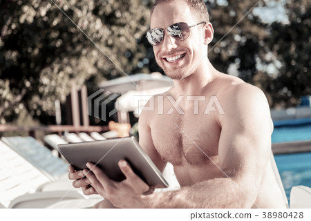 Well built young man with touchpad grinning 38980428