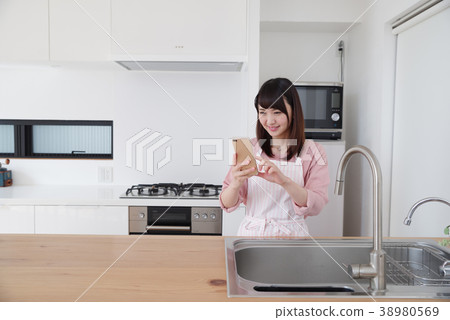 婦女運行的智能手機在廚房裡 婦女運行的智能手機在廚房裡 38980569