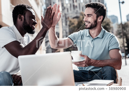 Best friends and coworkers high fiving outdoors Best friends and coworkers high fiving outdoors 38980908