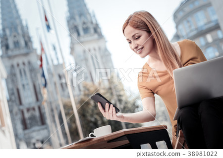 Beaming lady using smartphone outdoors Beaming lady using smartphone outdoors 38981022