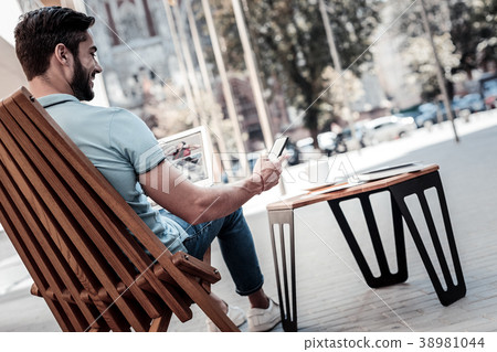 Smiling young man using smartphone while working 38981044