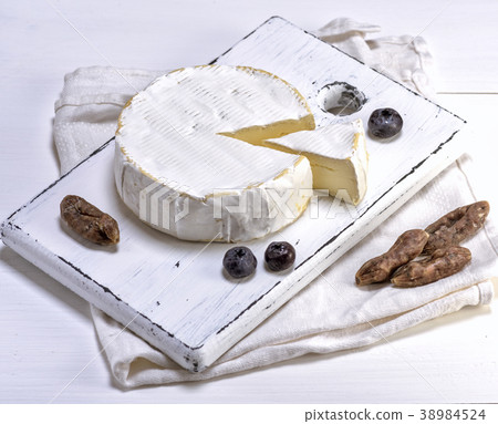 round Camembert cheese on a white wooden board 38984524