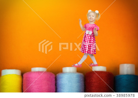 The girl 3 years is balancing on huge coils with threads. The girl 3 years is balancing on huge coils with threads. 38985978