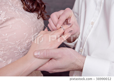 Close-up male and female hands while putting a 38990012