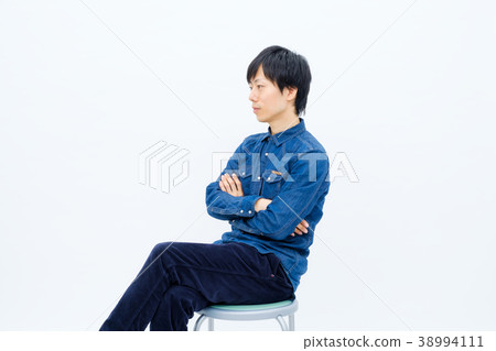 A man sitting in a chair and staring at something 38994111