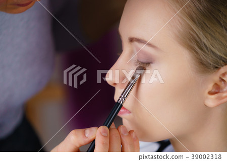 Woman getting make up done by artist 39002318