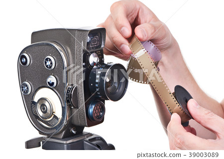 Retro mechanical movie camera and film in hands 39003089