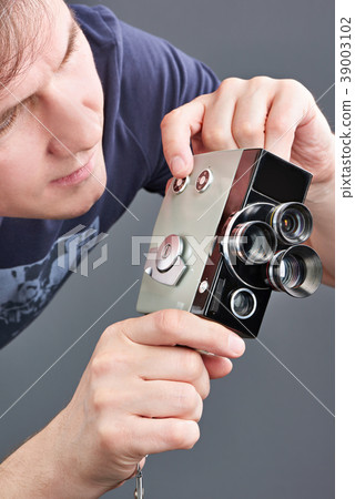 Retro mechanical movie camera in hands of man Retro mechanical movie camera in hands of man 39003102