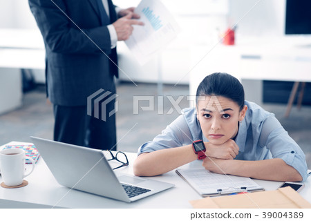 Exhausted female employee looking upset at work 39004389