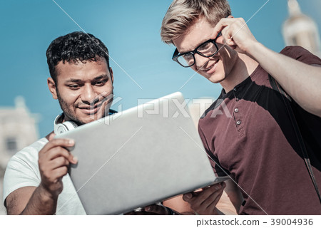 Pleasant smart students looking at the laptop Pleasant smart students looking at the laptop 39004936