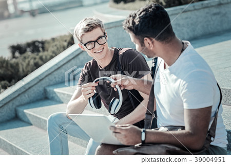 Nice young man giving headphones to his friend 39004951
