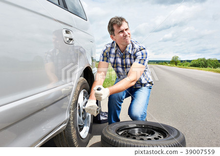 Man changing a spare tire of car 39007559