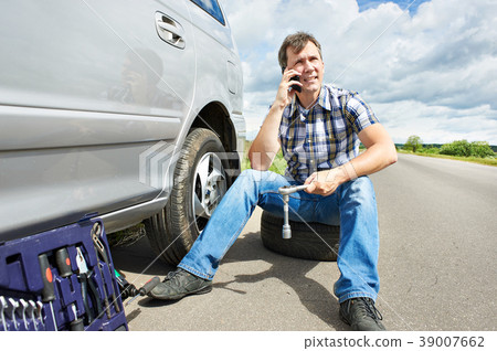 Man with phone calling in service spare tire car 39007662