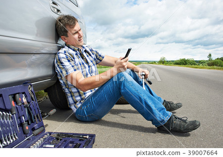Man with phone calling in service spare tire car 39007664