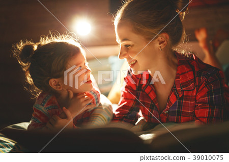 mother and child reading book in bed before going to sleep . mother and child reading book in bed before going to sleep . 39010075