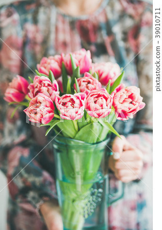 Woman in colorful dress holding bouquet of pink Woman in colorful dress holding bouquet of pink 39010711