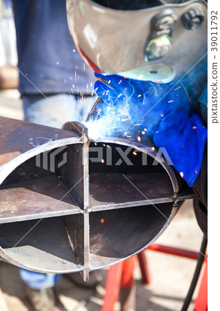 Worker welding in a factory. Welding on an 39011792