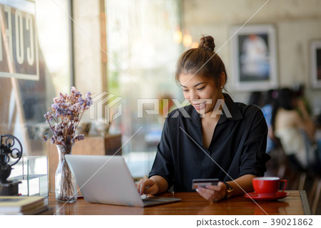 Asian woman paying online by laptop at coffee Asian woman paying online by laptop at coffee 39021862