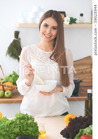 Young happy woman cooking in the kitchen. Healthy Young happy woman cooking in the kitchen. Healthy 39028944