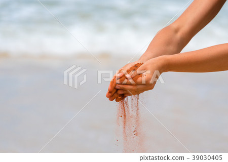 Woman hands holding red sand on the beach Woman hands holding red sand on the beach 39030405