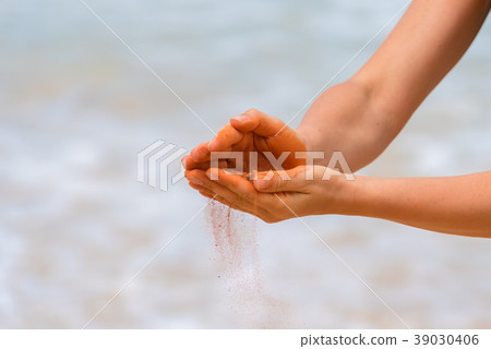Woman hands holding red sand on the beach Woman hands holding red sand on the beach 39030406