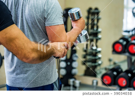 Back view man trains biceps with trainer in gym Back view man trains biceps with trainer in gym 39034038