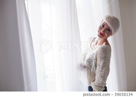 blonde with short hair stands at the window blonde with short hair stands at the window 39038134