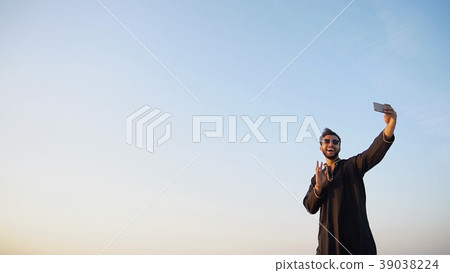 Modern male Arab traveler holds smartphone and 39038224