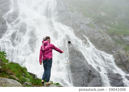 Female tourist observing beautiful waterfall in the mountains Female tourist observing beautiful waterfall in the mountains 39041006