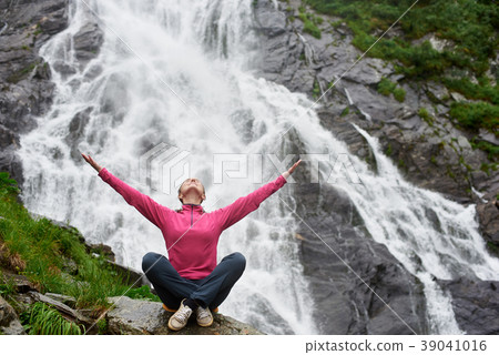 Female tourist sits against background of waterfall Balea in Romania Female tourist sits against background of waterfall Balea in Romania 39041016