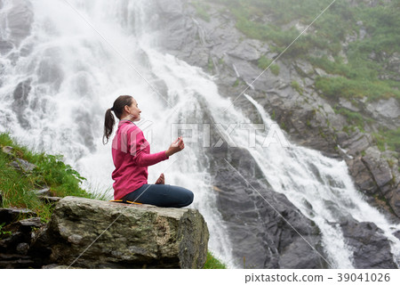 Attractive woman practising yoga on rock near beautiful Balea waterfall in Romania Attractive woman practising yoga on rock near beautiful Balea waterfall in Romania 39041026