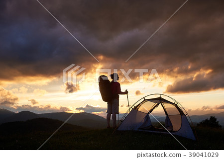 Silhouette of a female camper in the mountains on sunset 39041029