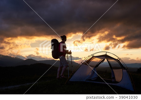 Hiker woman standing near the tent with backpack. 39041030