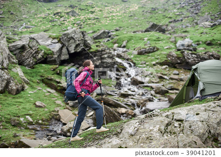 Female sporty climber walking up rocky slope of beautiful foggy mountains in Romania. Female sporty climber walking up rocky slope of beautiful foggy mountains in Romania. 39041201